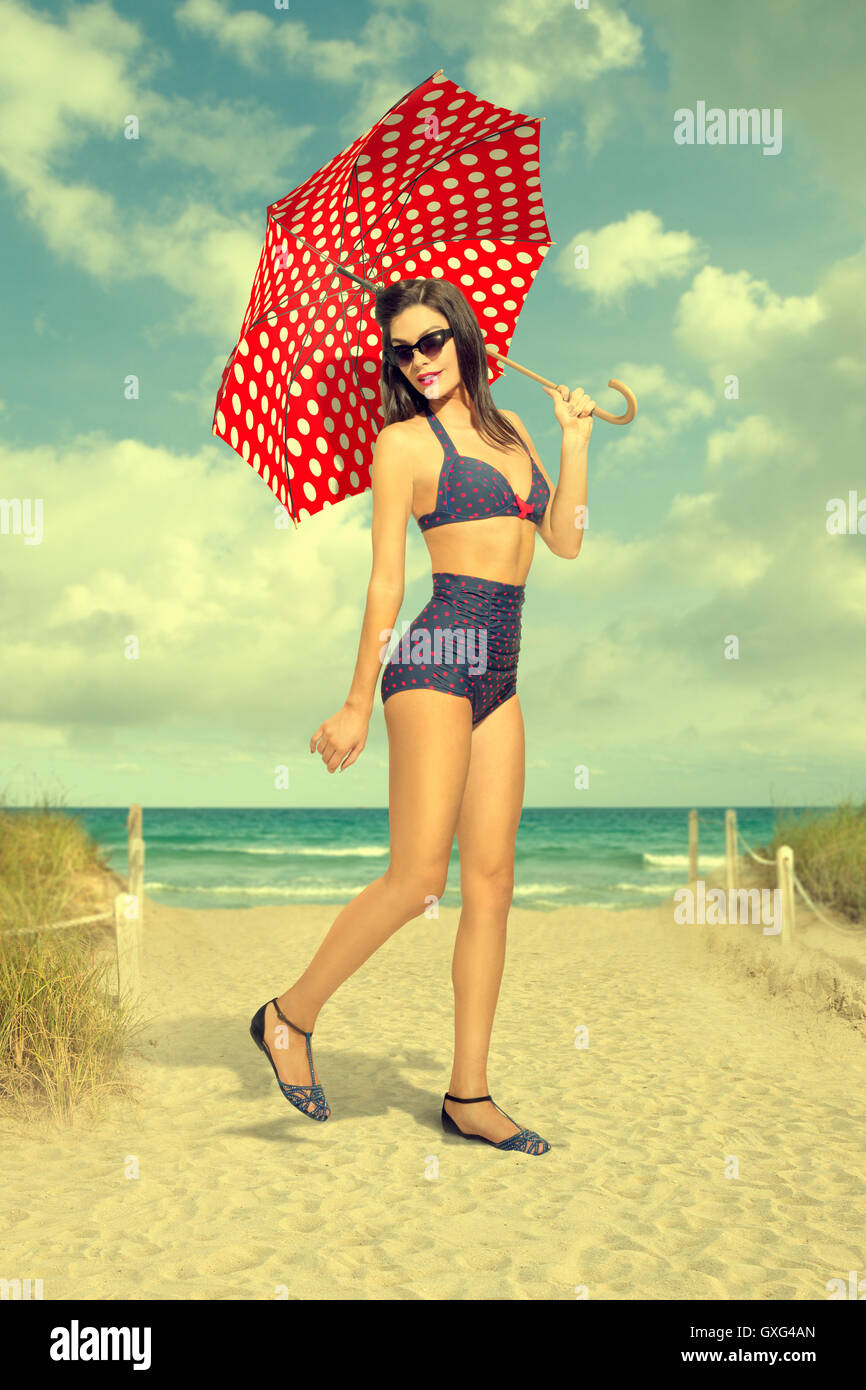 Caucasian woman holding polka-dot umbrella at beach Stock Photo