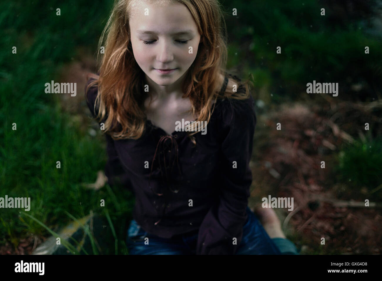 Caucasian girl sitting in grass with eyes closed Stock Photo - Alamy
