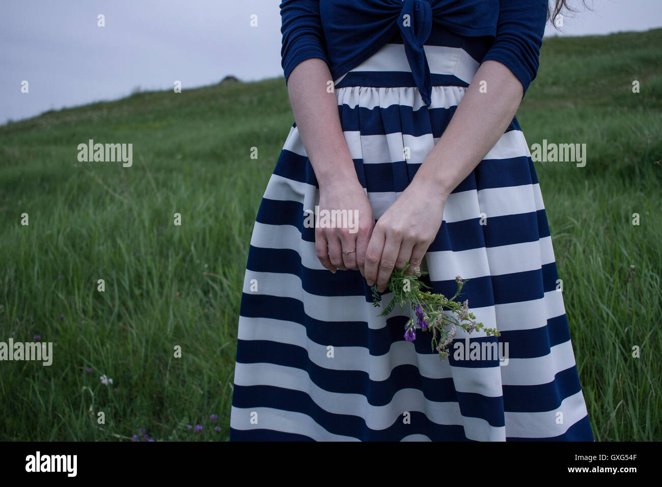 Caucasian woman holding wildflowers in field of grass Stock Photo