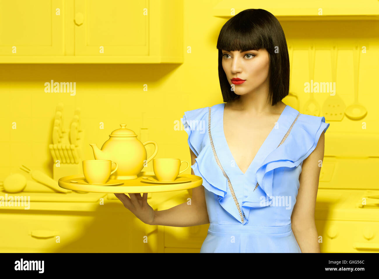 Caucasian woman in yellow old-fashioned kitchen holding tea service Stock Photo