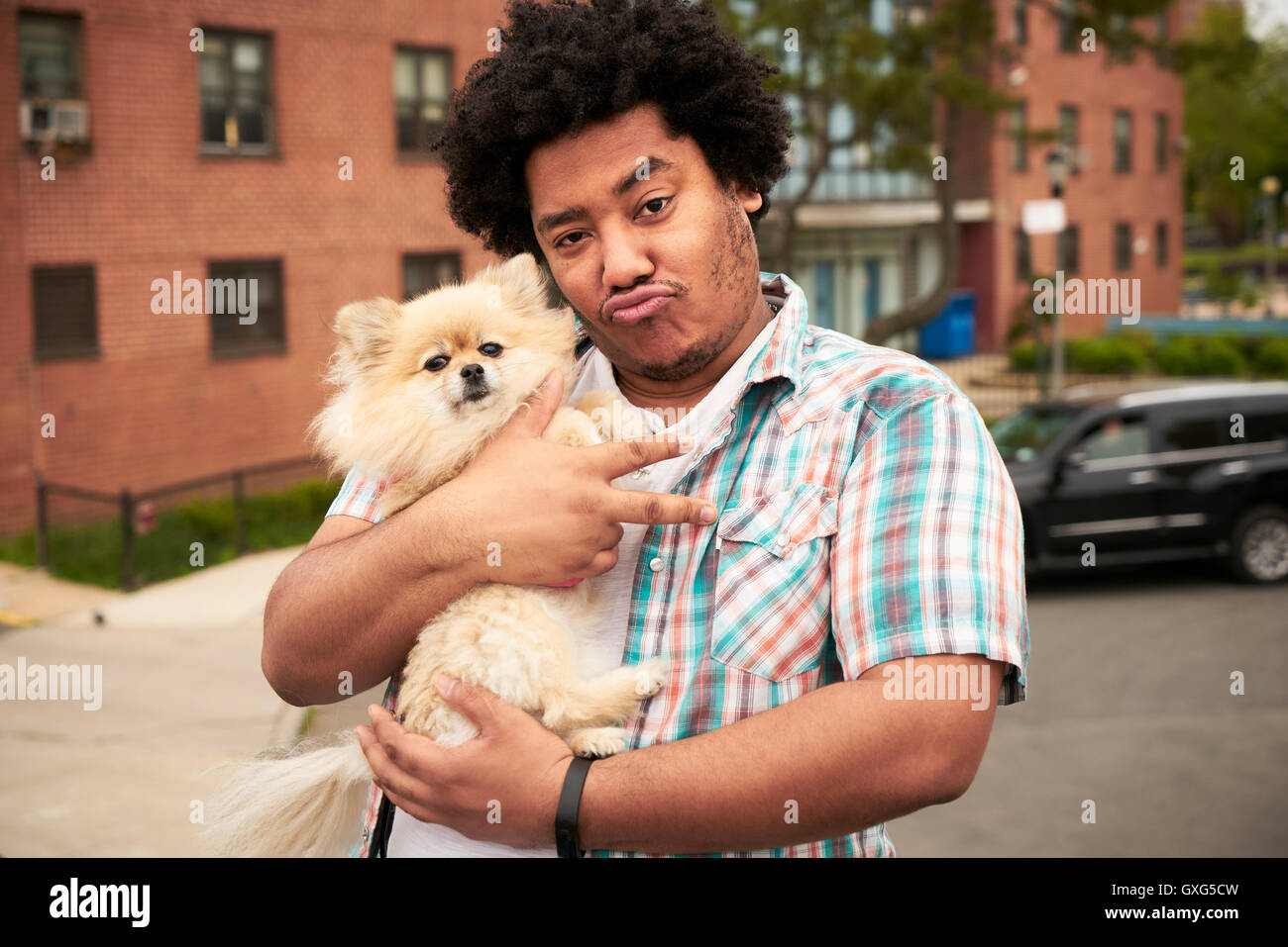 Mixed Race man gesturing peace with dog in city Stock Photo