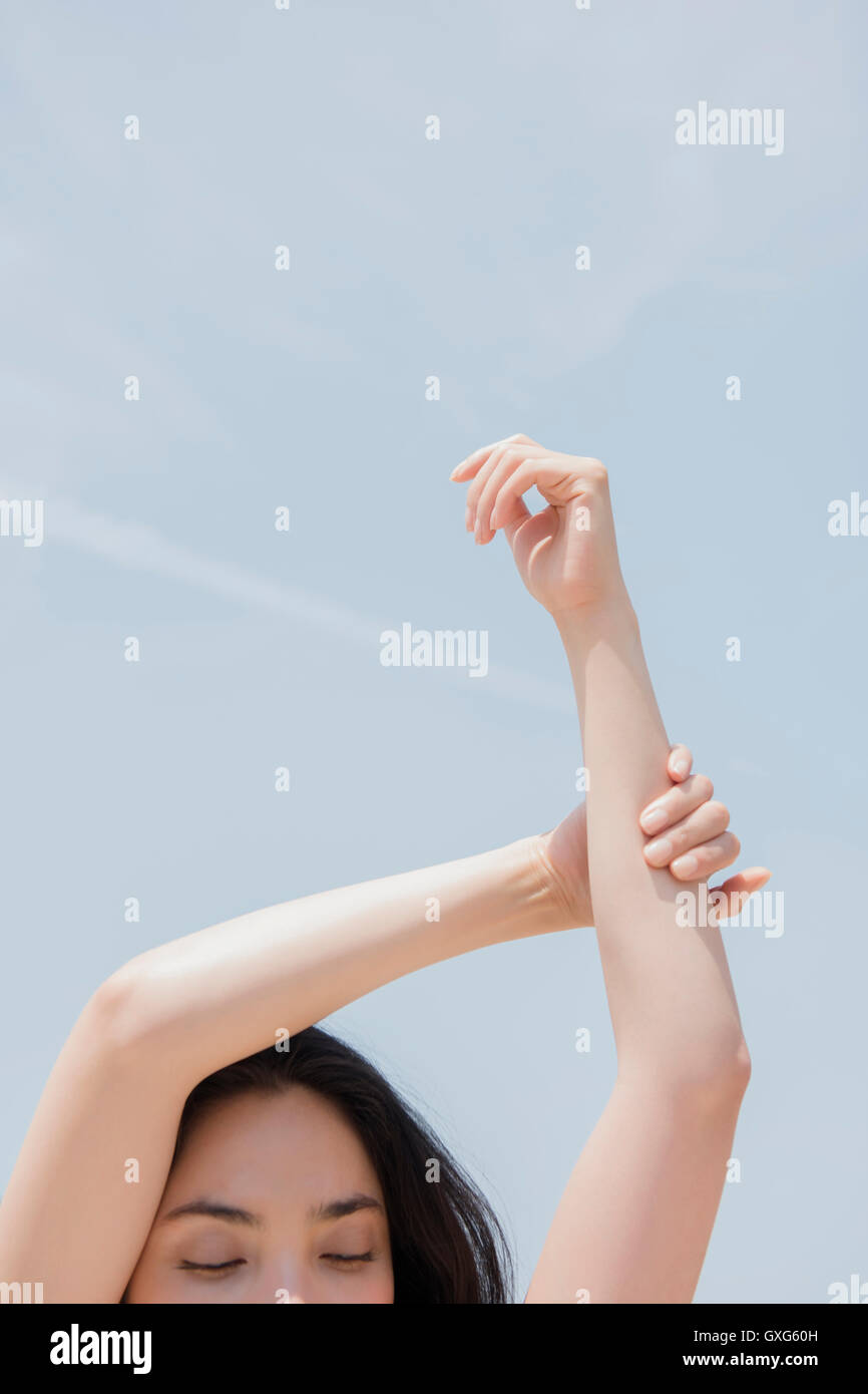 Hispanic woman stretching arms under blue sky Stock Photo