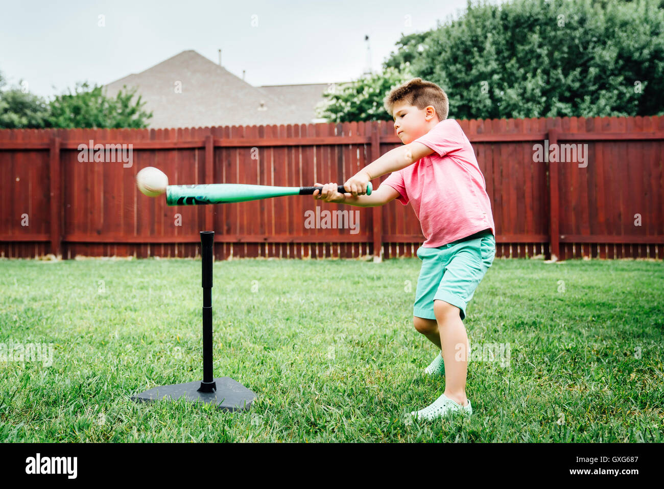 Caucasian boy hitting baseball off tee in backyard Stock Photo Alamy