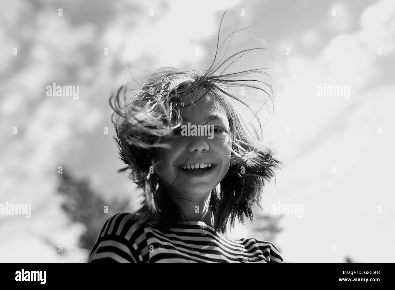 Smiling Caucasian girl with hair blowing in wind Stock Photo