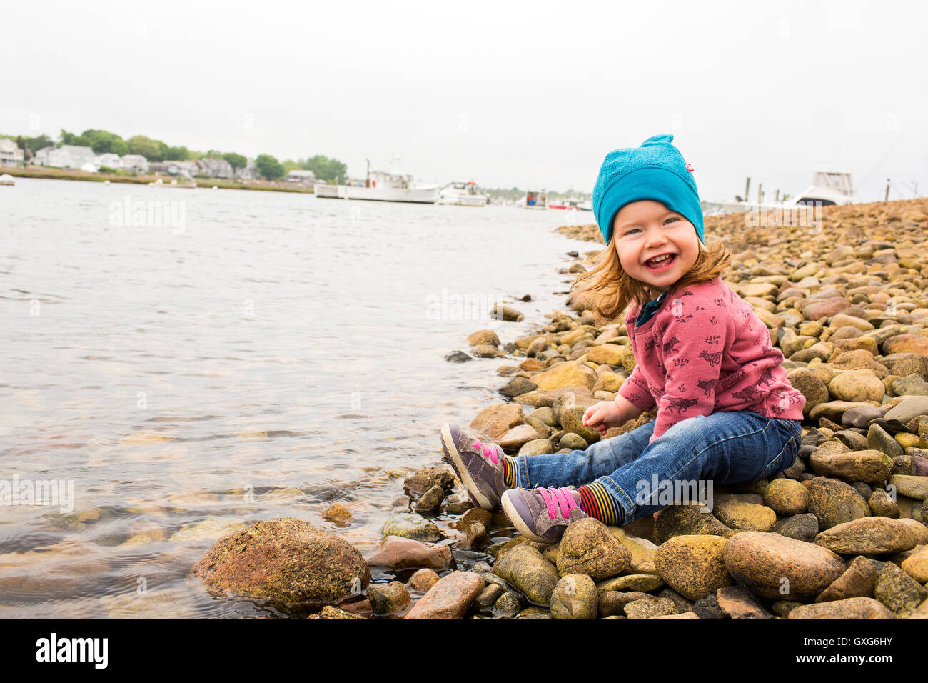 Smiling Caucasian girl sitting on rocks at river Stock Photo - Alamy
