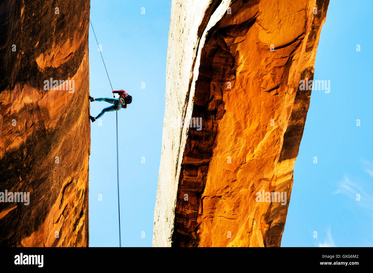 Rock climber using rope on arch Stock Photo