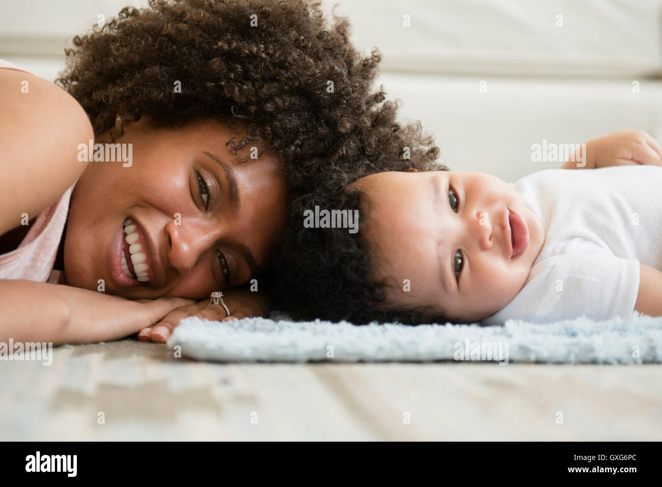 Mother and baby son laying head to head on floor Stock Photo