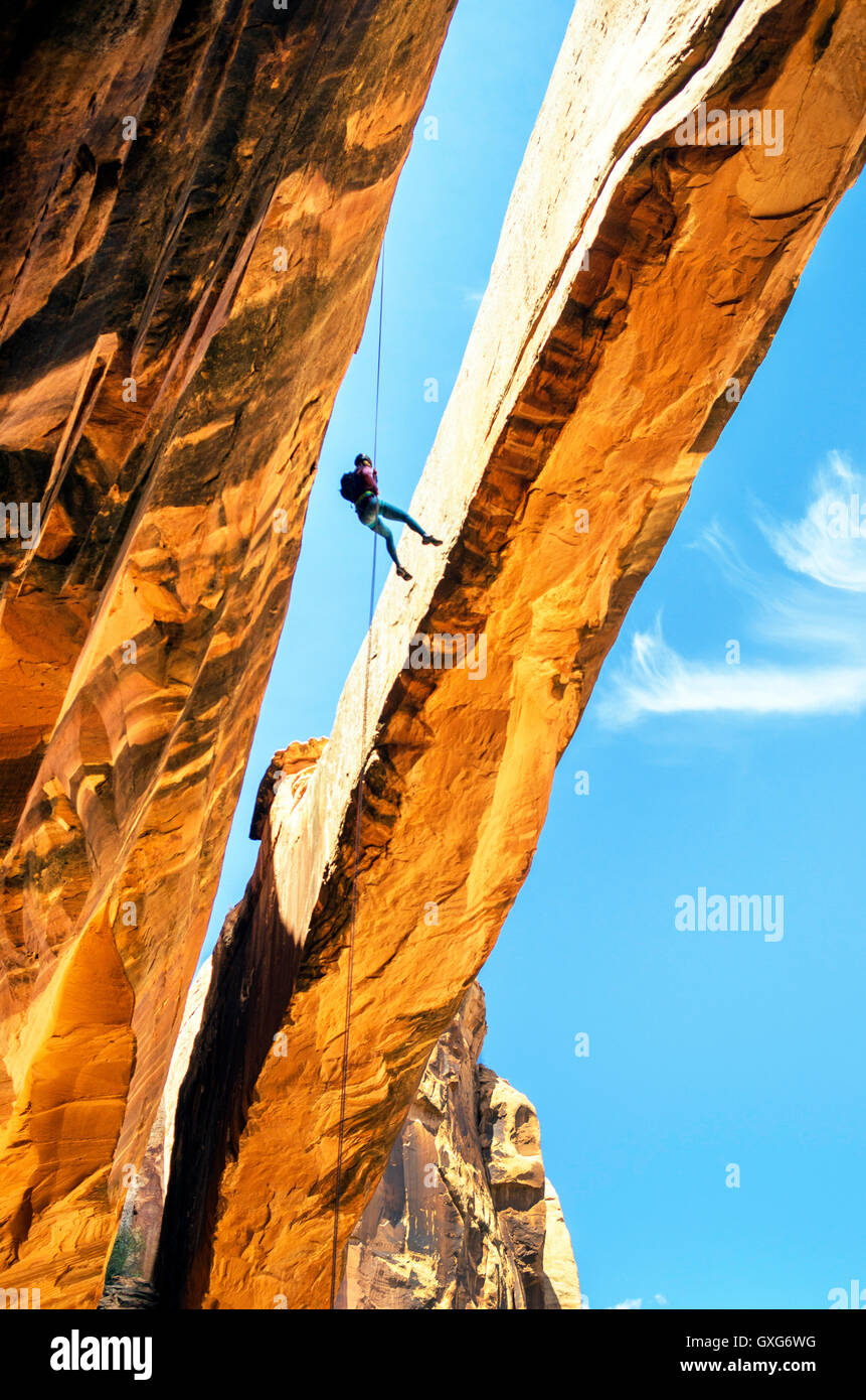 Rock climber hanging on rope on arch Stock Photo
