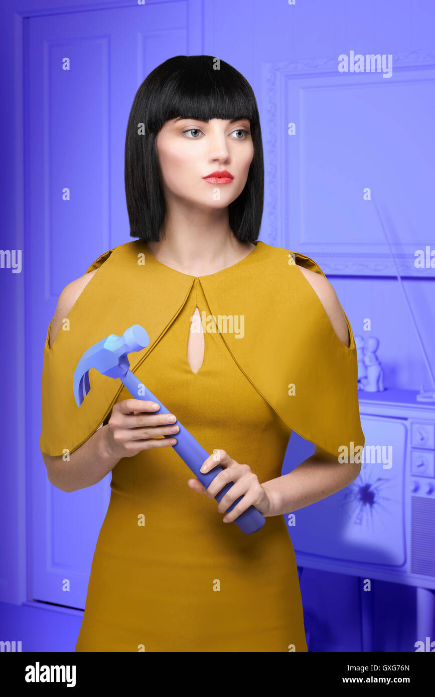 Caucasian woman in purple old-fashioned livingroom holding hammer Stock Photo