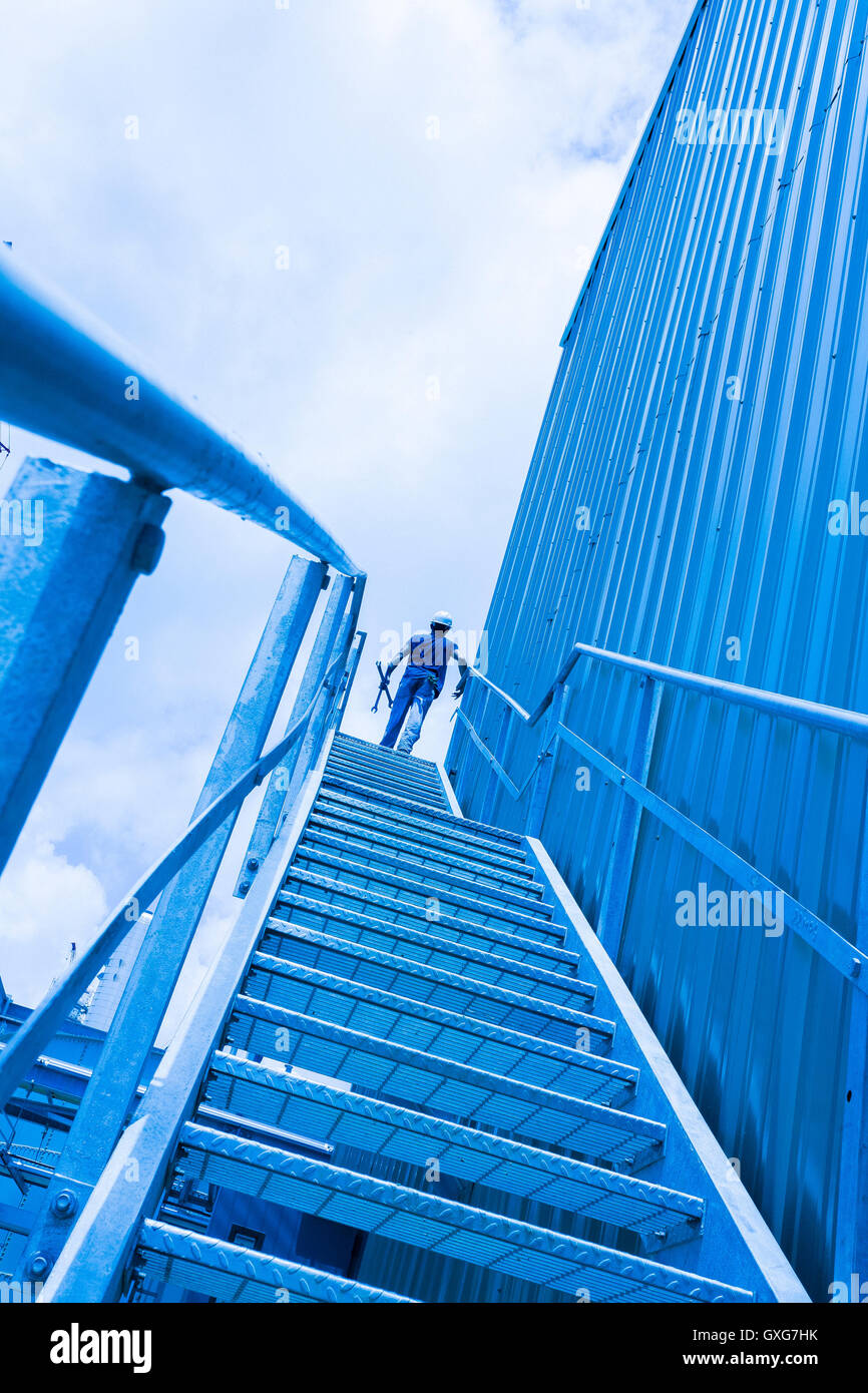 Blue collar worker at top of industrial staircase Stock Photo