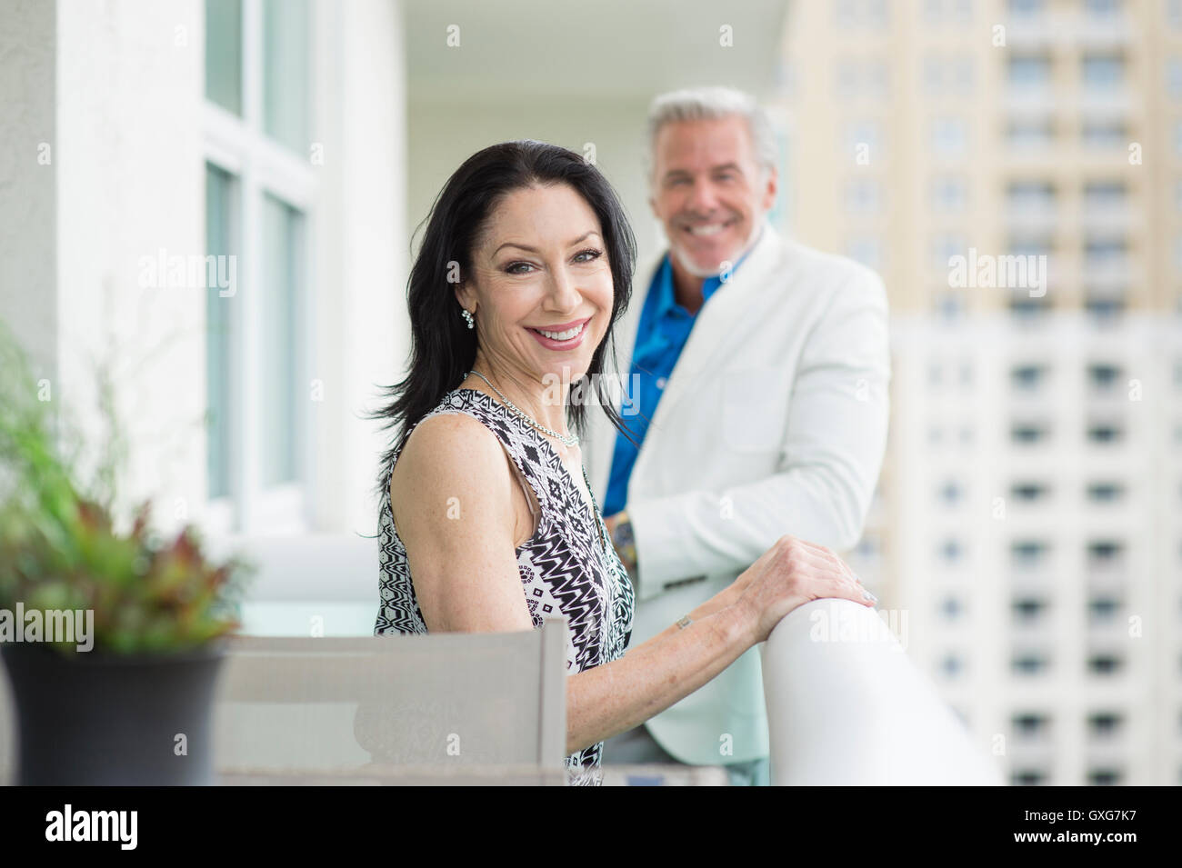 Smiling Caucasian couple standing on balcony Stock Photo