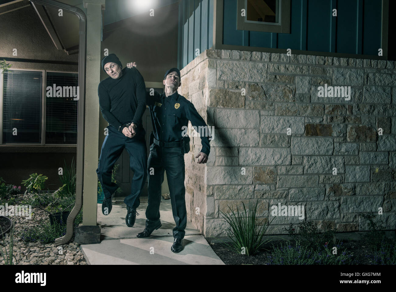 Caucasian police lifting burglar in handcuffs Stock Photo