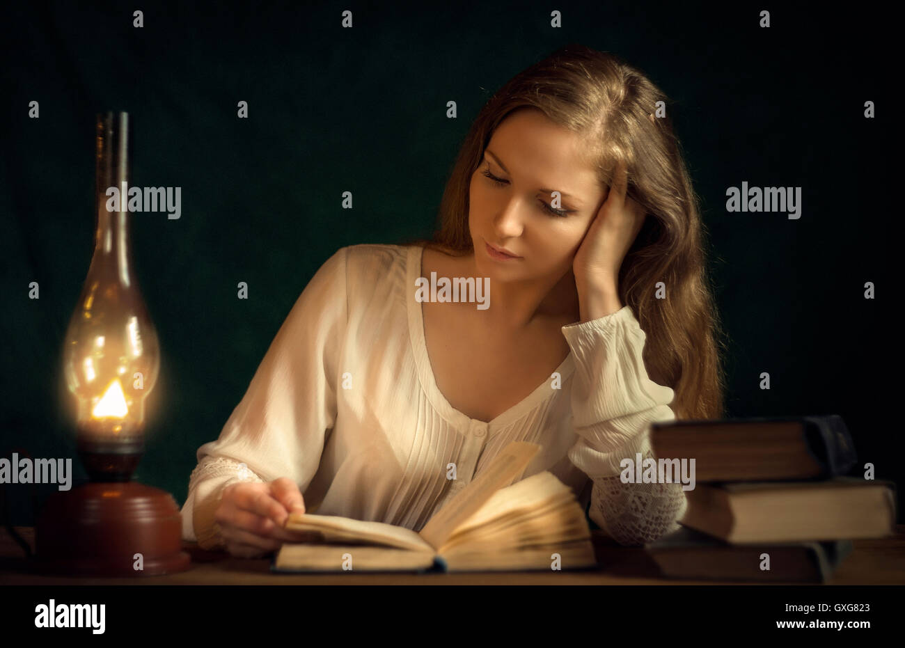 Caucasian woman reading book by candlelight Stock Photo - Alamy