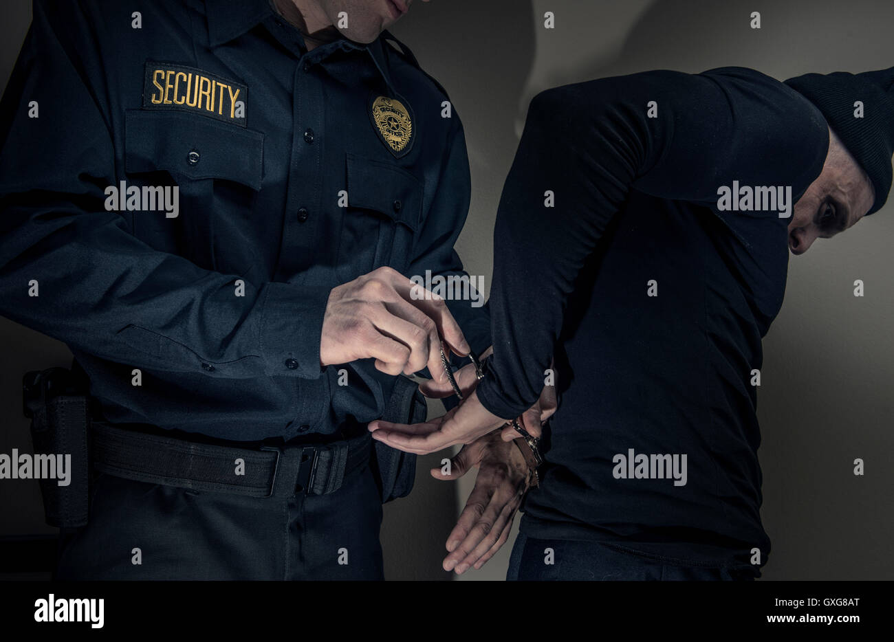 Caucasian police officer handcuffing burglar Stock Photo