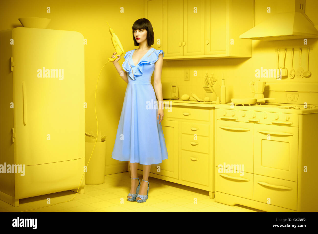 Caucasian woman in yellow old-fashioned kitchen holding power drill Stock Photo