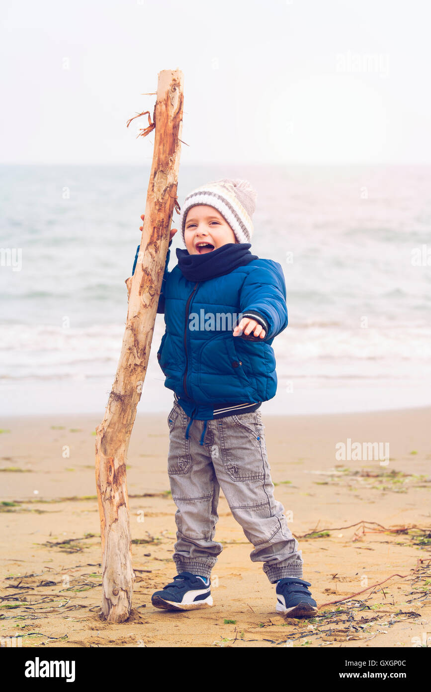 child climbing on a pile of sand in Winter Beach Stock Photo