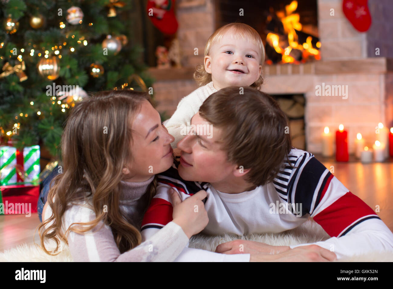 Happy parents and child boy have a fun near Christmas tree at home. Father, mother, son celebrating New Year together Stock Photo