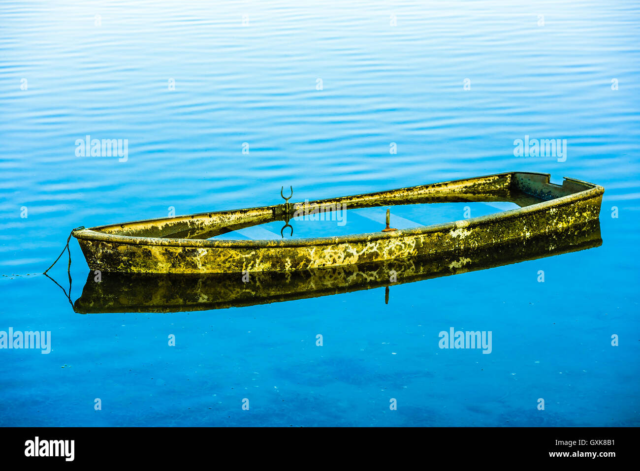 Small abandoned boat almost completely submerged in the seawater. Stock Photo