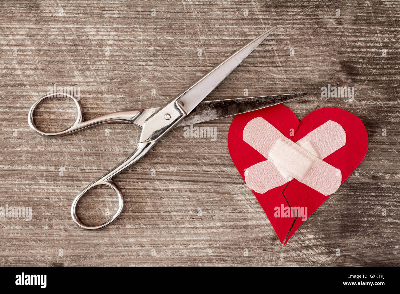 Broken heart with bandage and scissors on a wooden background Stock ...