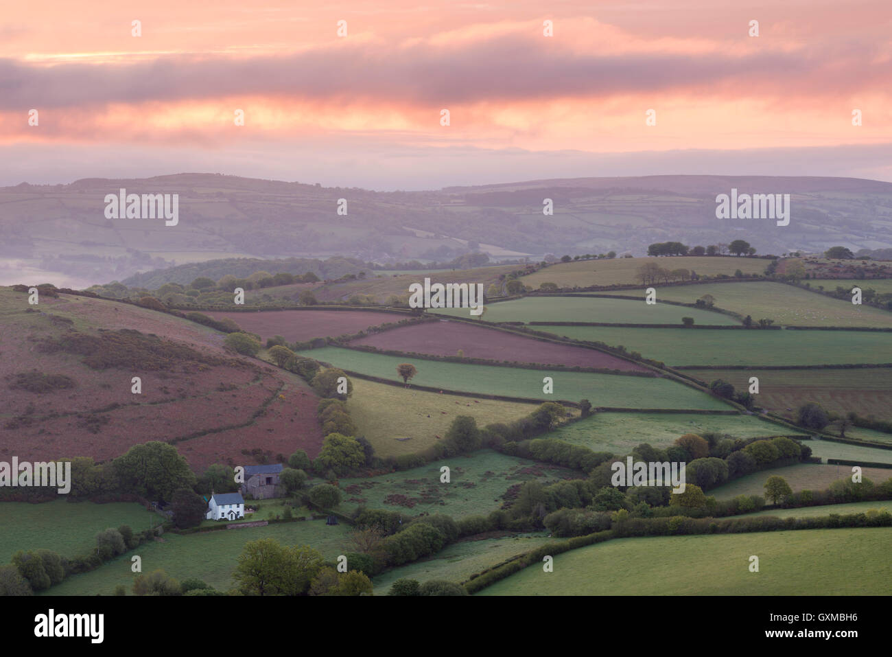 Colourful sunrise over Quintatown farm and the rolling fields of Dartmoor National Park near Chagford, Devon, England. Stock Photo