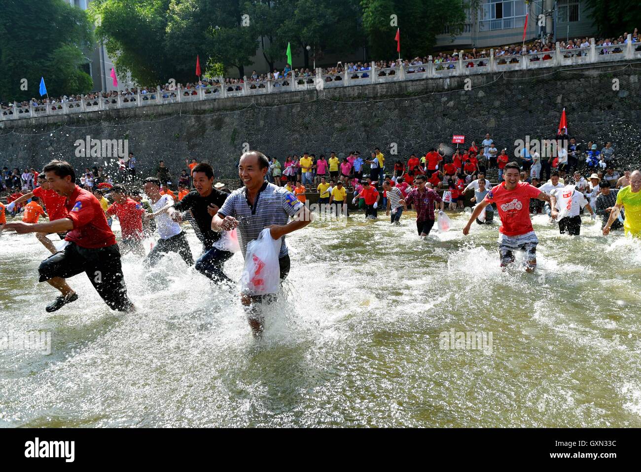 (160916) -- ENSHI, Sept. 16, 2016 (Xinhua) -- Local people gather to catch fish by hands in a river to celebrate a good harvest in Xuanen County, central China's Hubei Province, Sept. 16, 2016. (Xinhua/Song Wen) (cxy) Stock Photo