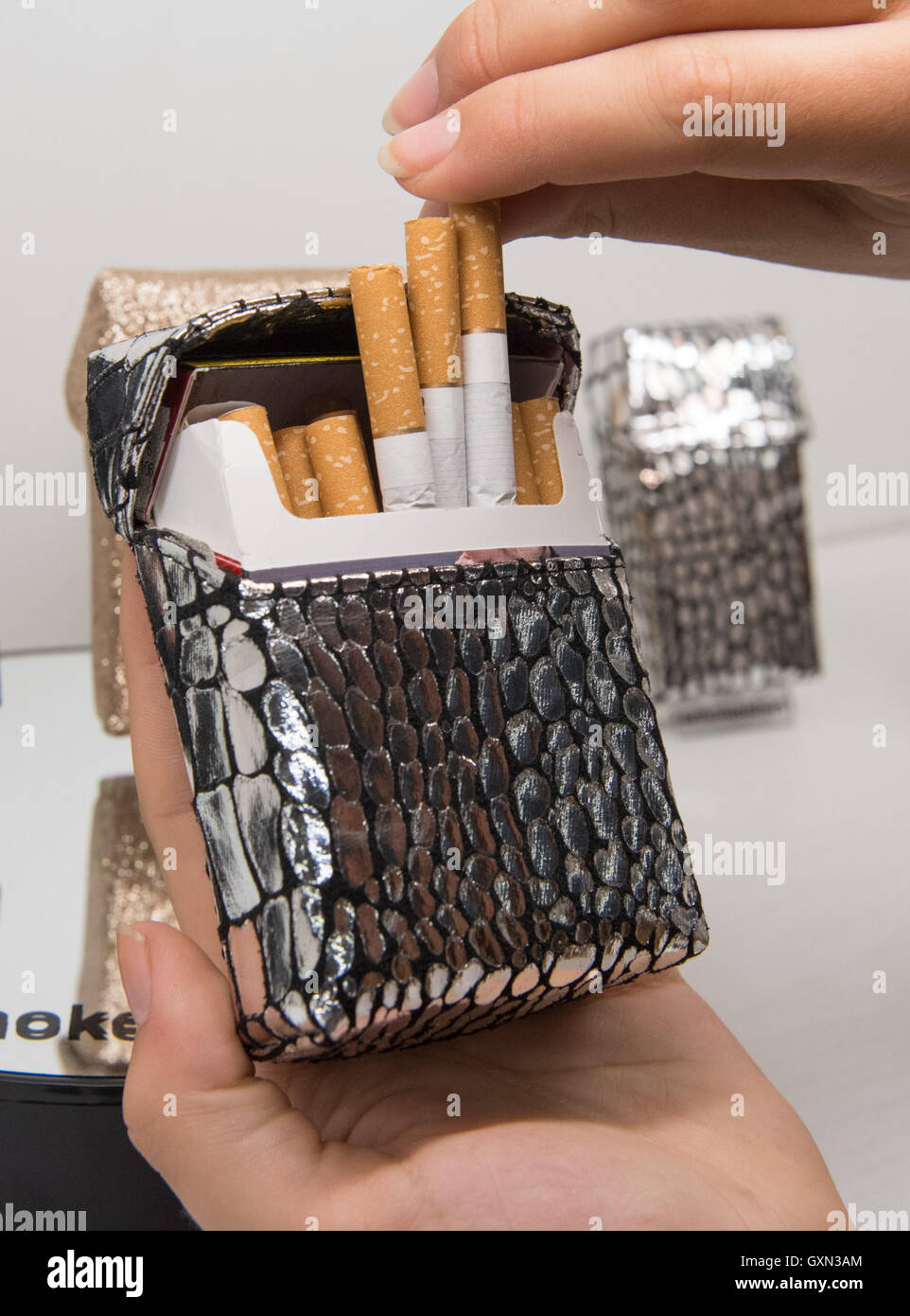 Dortmund, Germany. 16th Sep, 2016. A woman takes a cigarette from a designer  case for cigarette packs in the model 'Treasure' from the Smokeshirt  collection by the Lifestyle and Fashion AG at