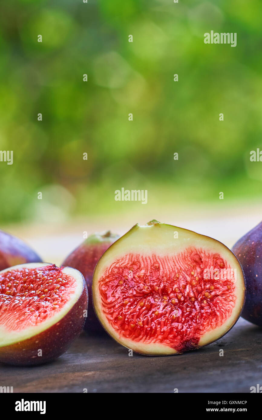 Fresh ripe black figs on rustic grey wooden table with green blurry background. Copy space Stock Photo
