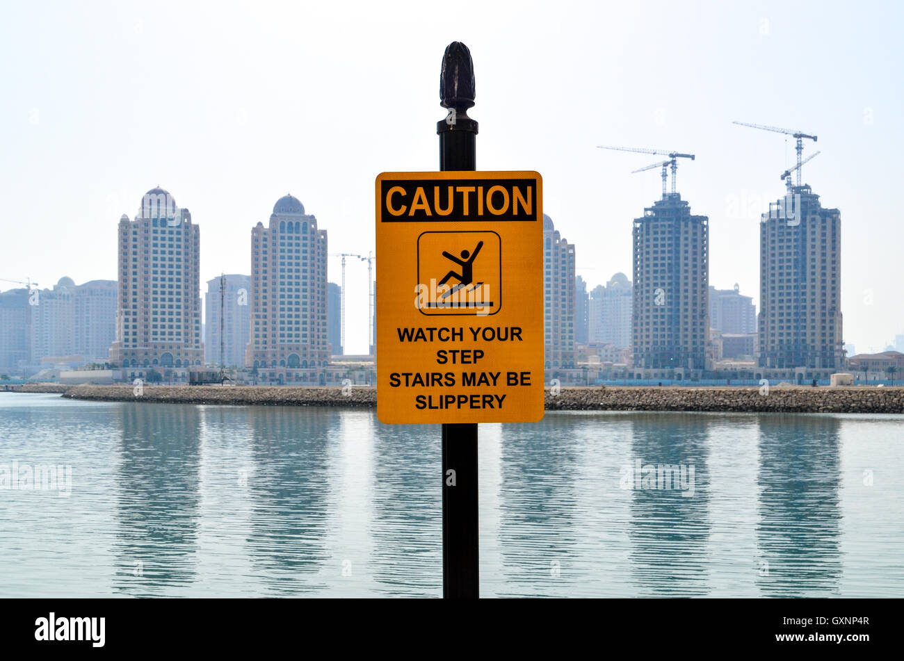 Caution sign in Doha, Qatar, with cranes building new residential towers Stock Photo