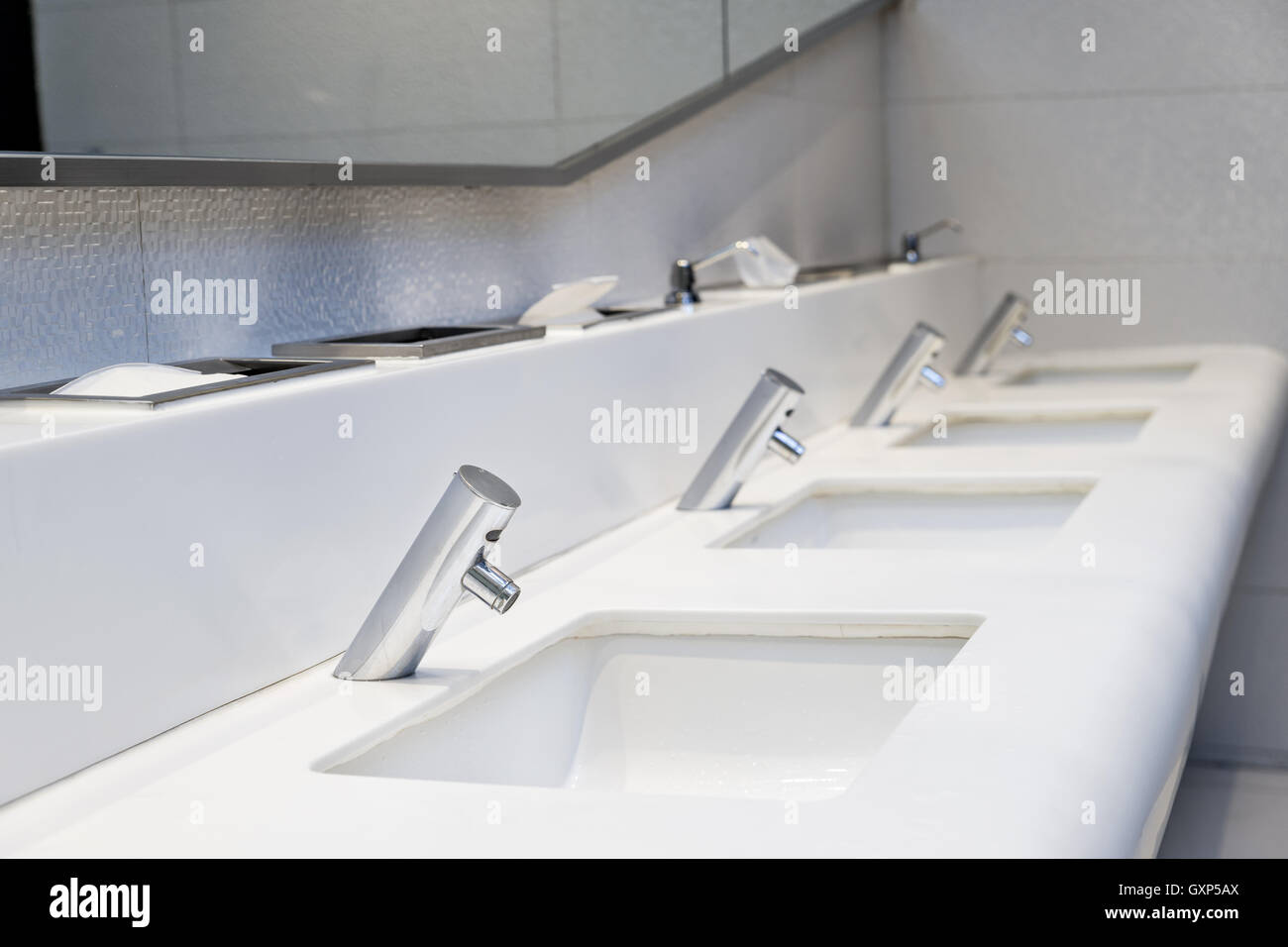 Interior of public toilet. Many faucet and sink in public toilet at hotel. Stock Photo