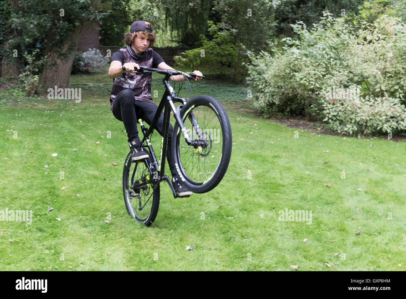 Teenage boy doing a wheelie on his bicycle, Berkshire UK Stock Photo
