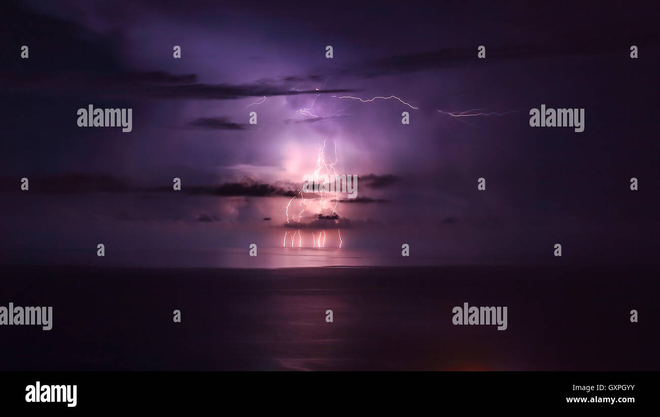 Purple lightning over the sea, powerful thunderbolt, amazing night landscape, stormy weather in the sea Stock Photo