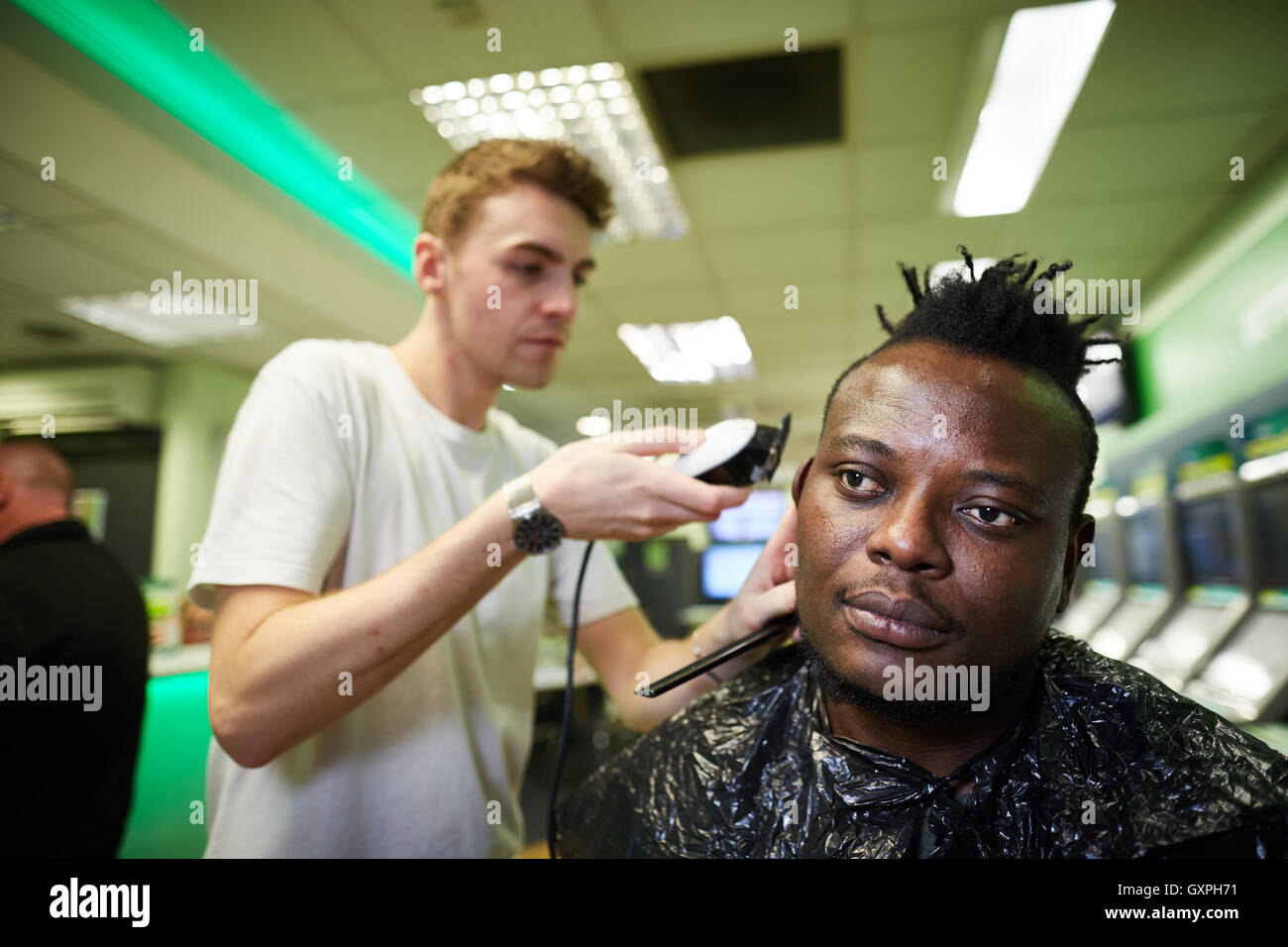 Black male has haircut shaved head at PaddyPower manchester as a PR marketing stunt Stock Photo