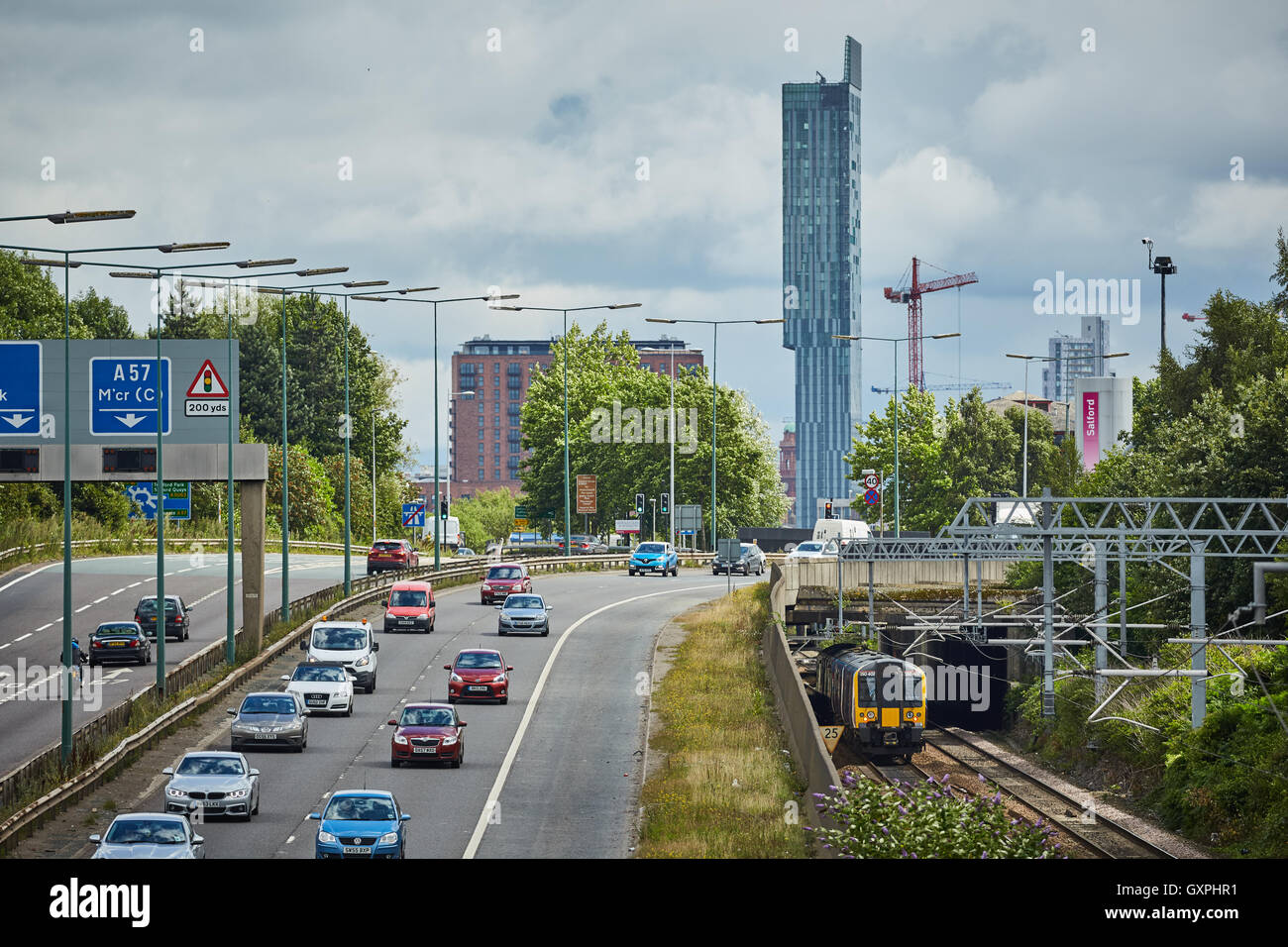 M602 Motorway Salford train Beetham Tower   Local train heading to manchester cars leaving two lanes  carriageway automobile aut Stock Photo