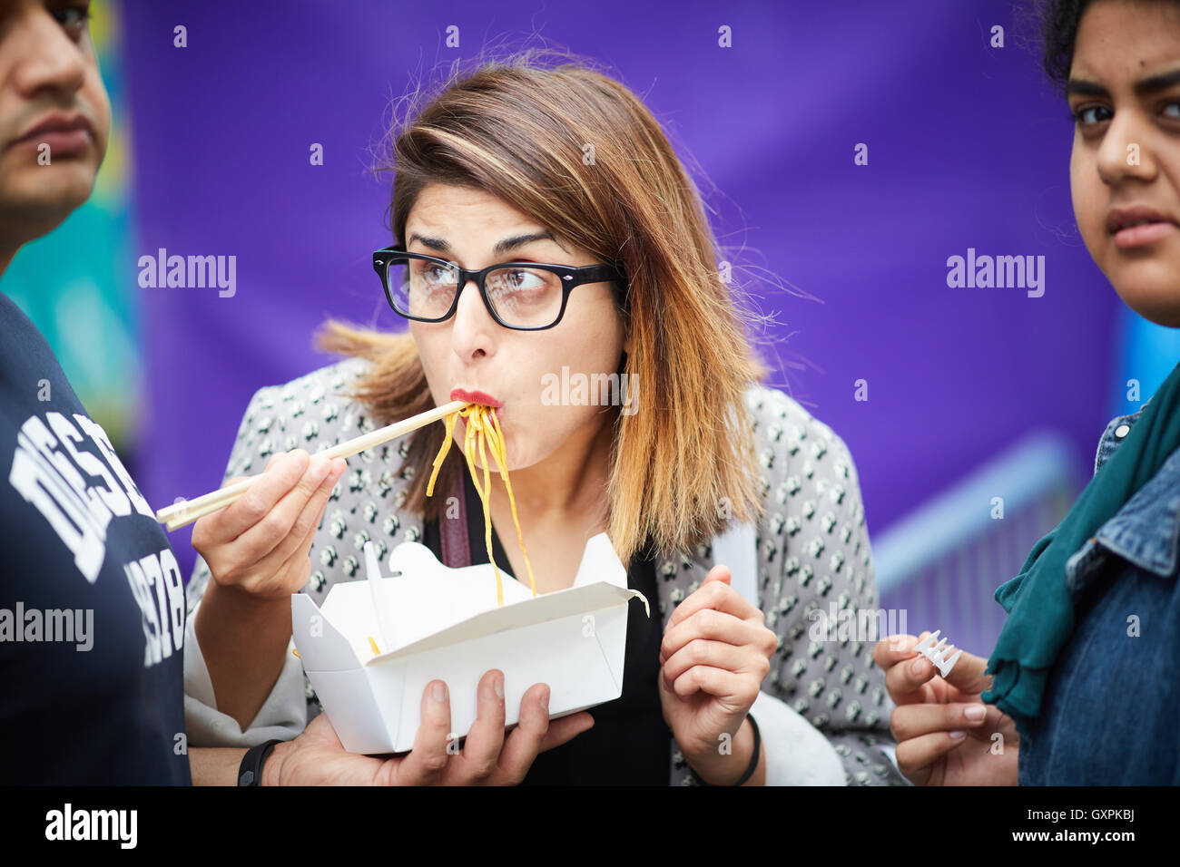 Bolton Food and Drink Festival  Eating noodles from box outside tale away chop sticks mouth full food carton box paper card card Stock Photo