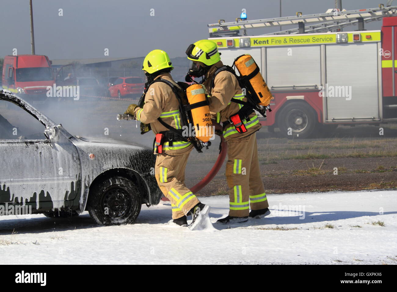 Firefighters wearing breathing apparatus tackle a vehicle fire using ...