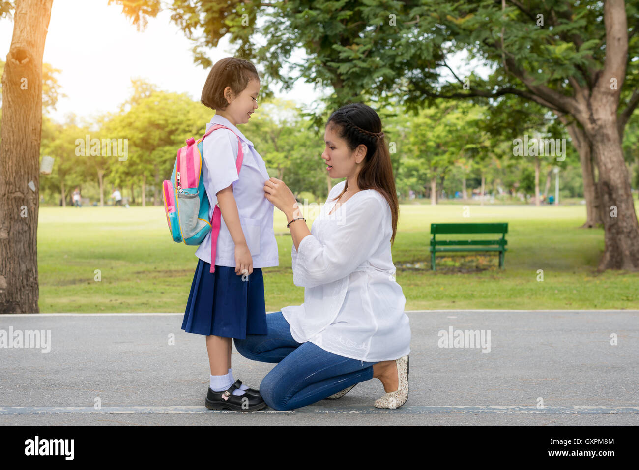 Back to school. Happy Asian mother with kids student in school. Asian mother adjusting kids student shirt in school. Stock Photo