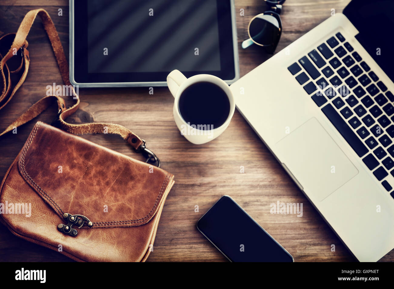Working place: laptop, tablet, phone, cup of coffee and stylish bag on the table of a business woman, lifestyle of modern people Stock Photo