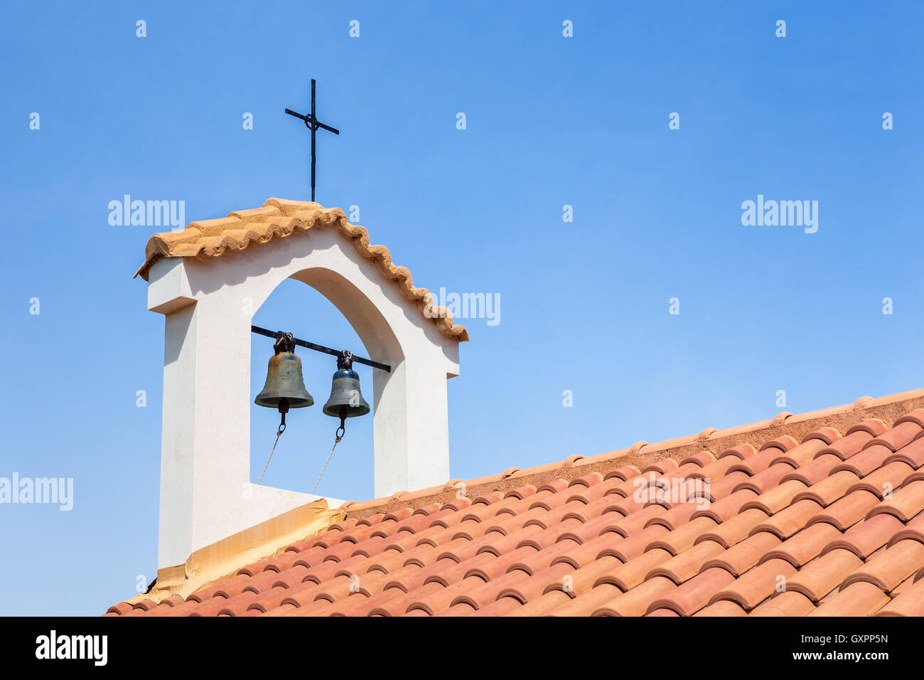 Churchtower on orange roof with bells and cross Stock Photo