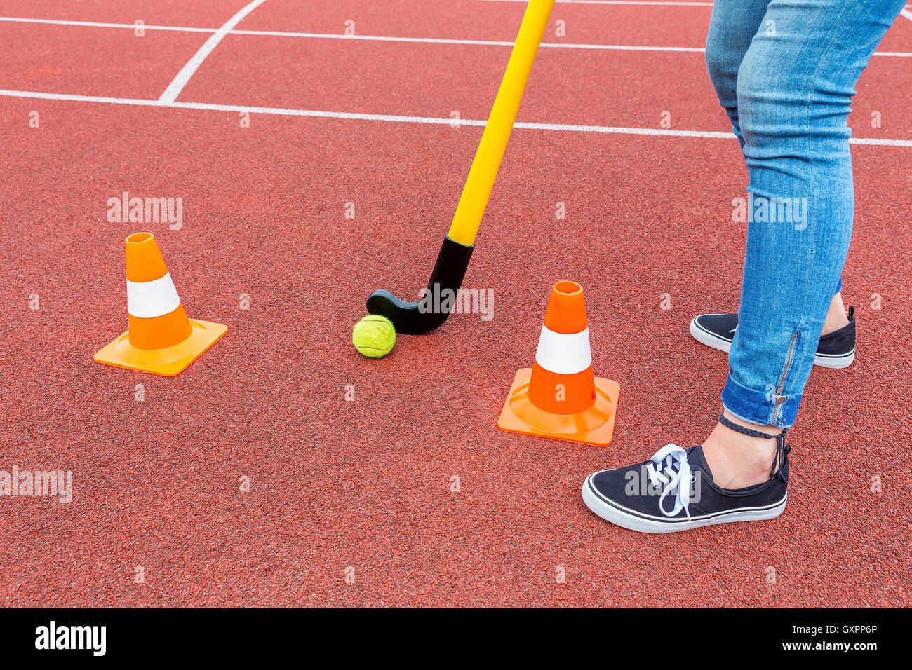 Legs of teenage girl as hockey player with stick ball and orange pawns Stock Photo
