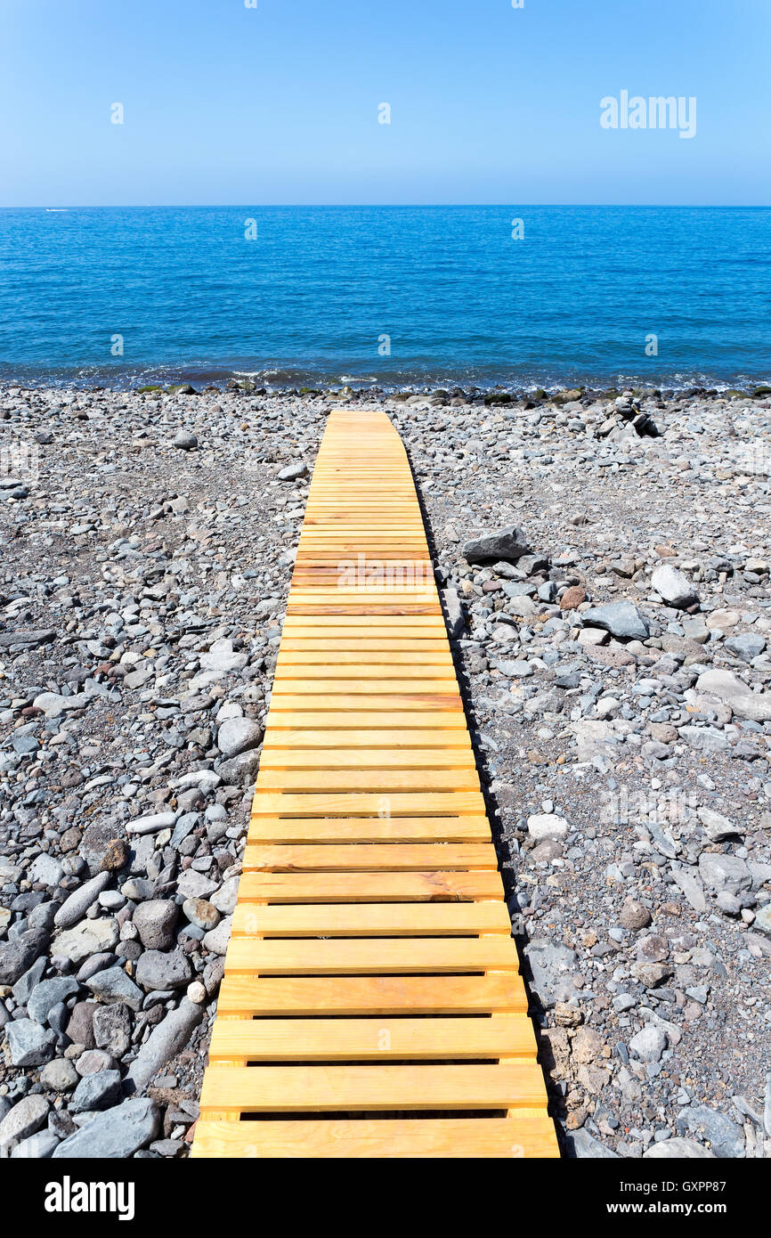 Wooden footpath on grey stony beach leading to portuguese ocean Stock Photo