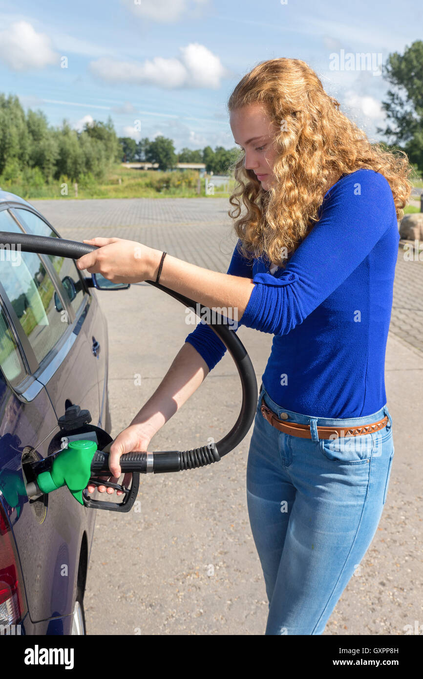 Young caucasian woman filling up tank of car with benzine Stock Photo