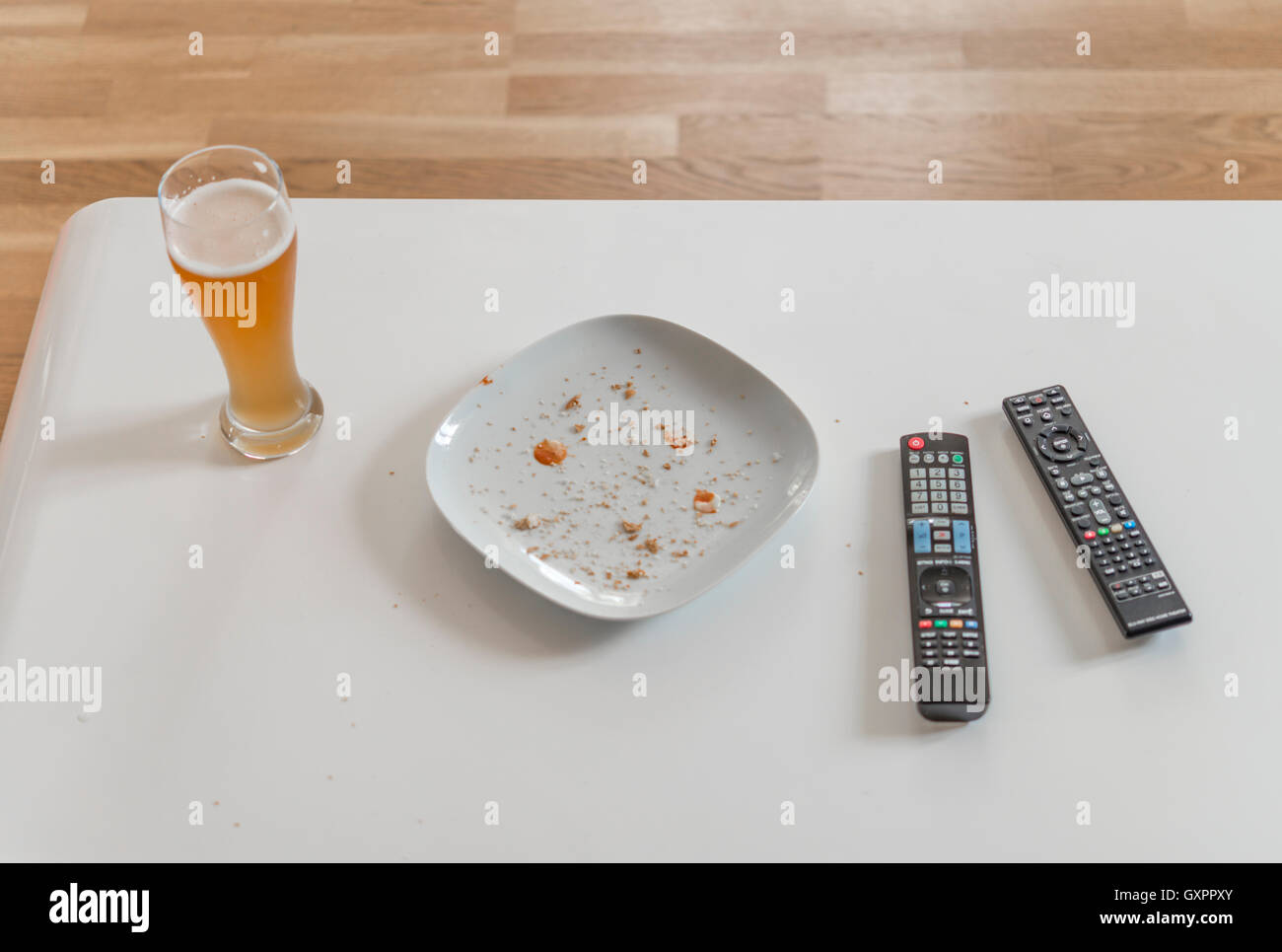 Living room table with beer and empty dish and remote control Stock Photo