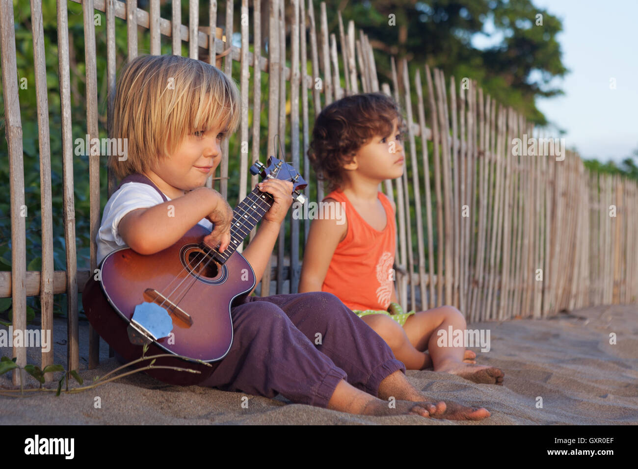 Little happy children have fun, play music on Hawaiian guitar ukulele
