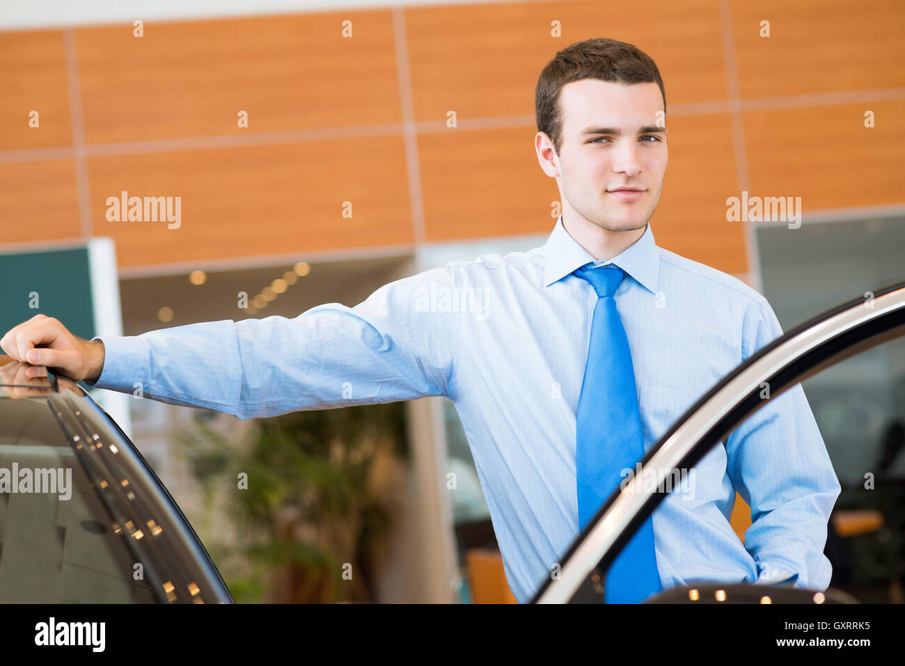 dealer stands near a new car in the showroom Stock Photo Alamy
