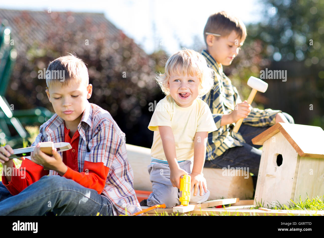 Happy kids boys brothers making wooden birdhouse by hands Stock Photo