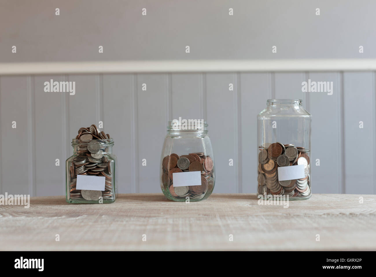 Glass jars with coins and blank labels Stock Photo