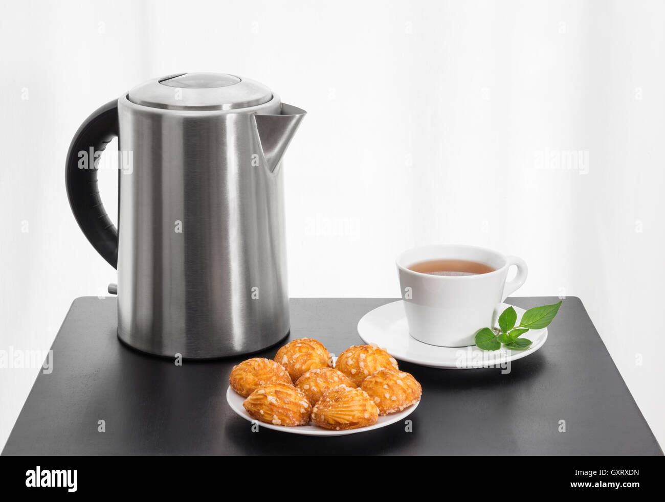 https://c8.alamy.com/comp/GXRXDN/electric-kettle-cup-of-tea-and-cookies-on-a-table-GXRXDN.jpg