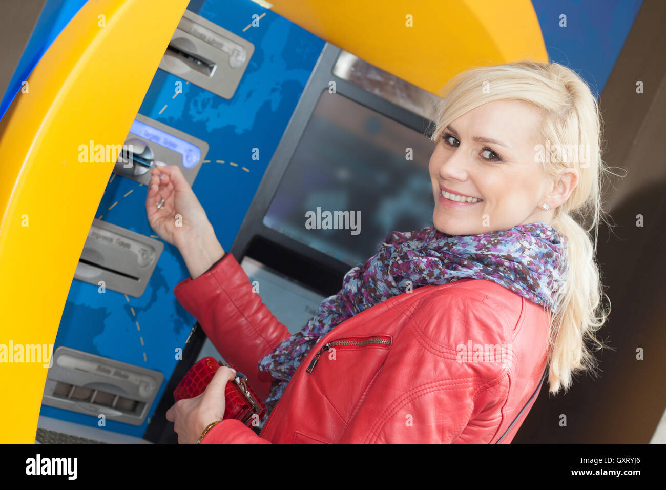 Smiling woman inserting her card in an ATM Stock Photo