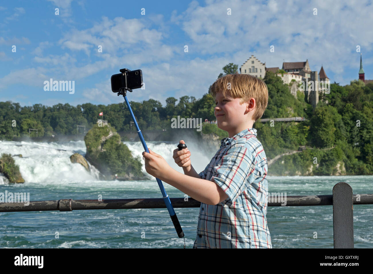young boy taking selfies, River Rhine Falls and Laufen Castle near Schaffhausen, Neuhausen am Rheinfall, Switzerland Stock Photo