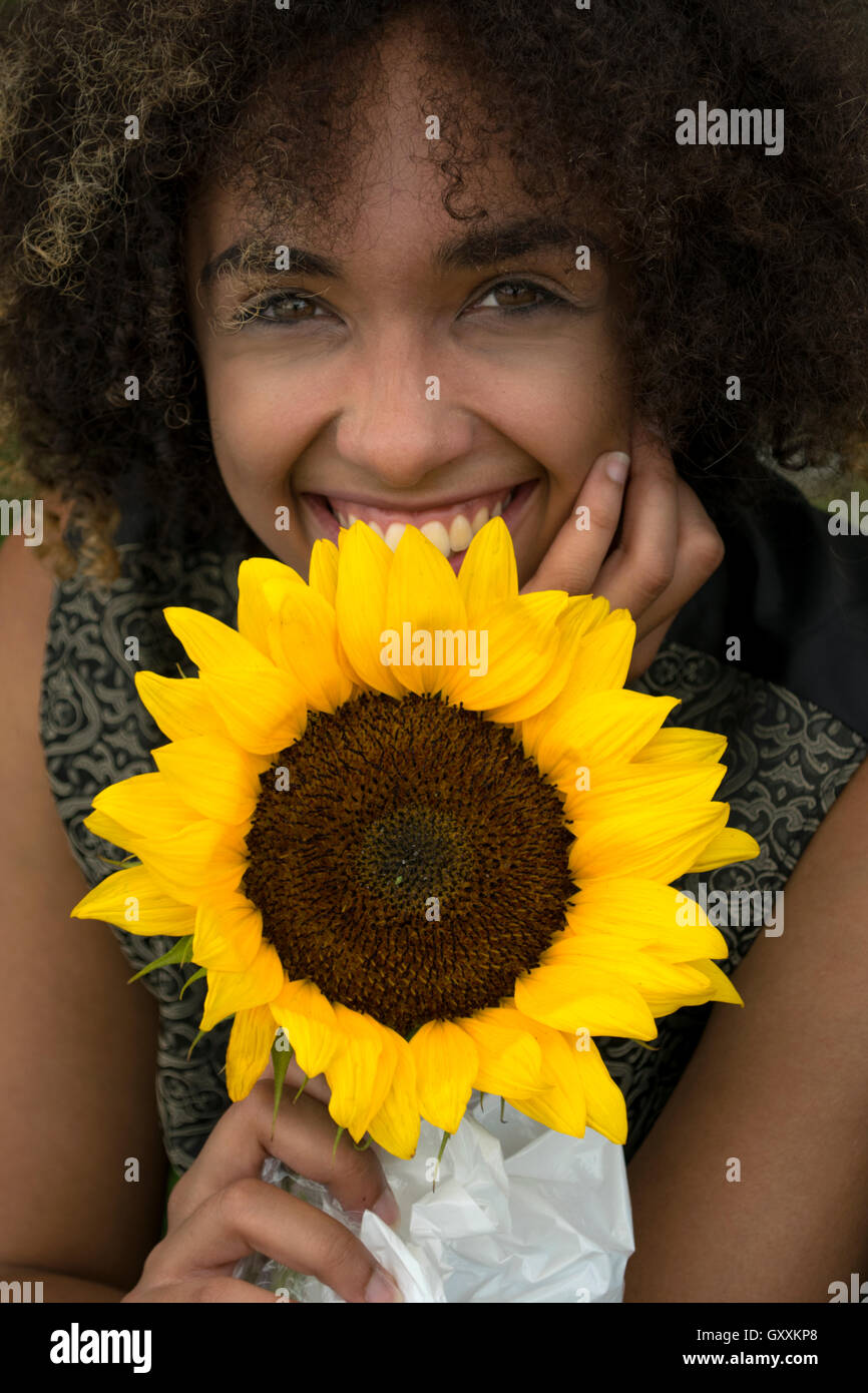 A smiling young African American woman holding a sunflower Stock Photo ...